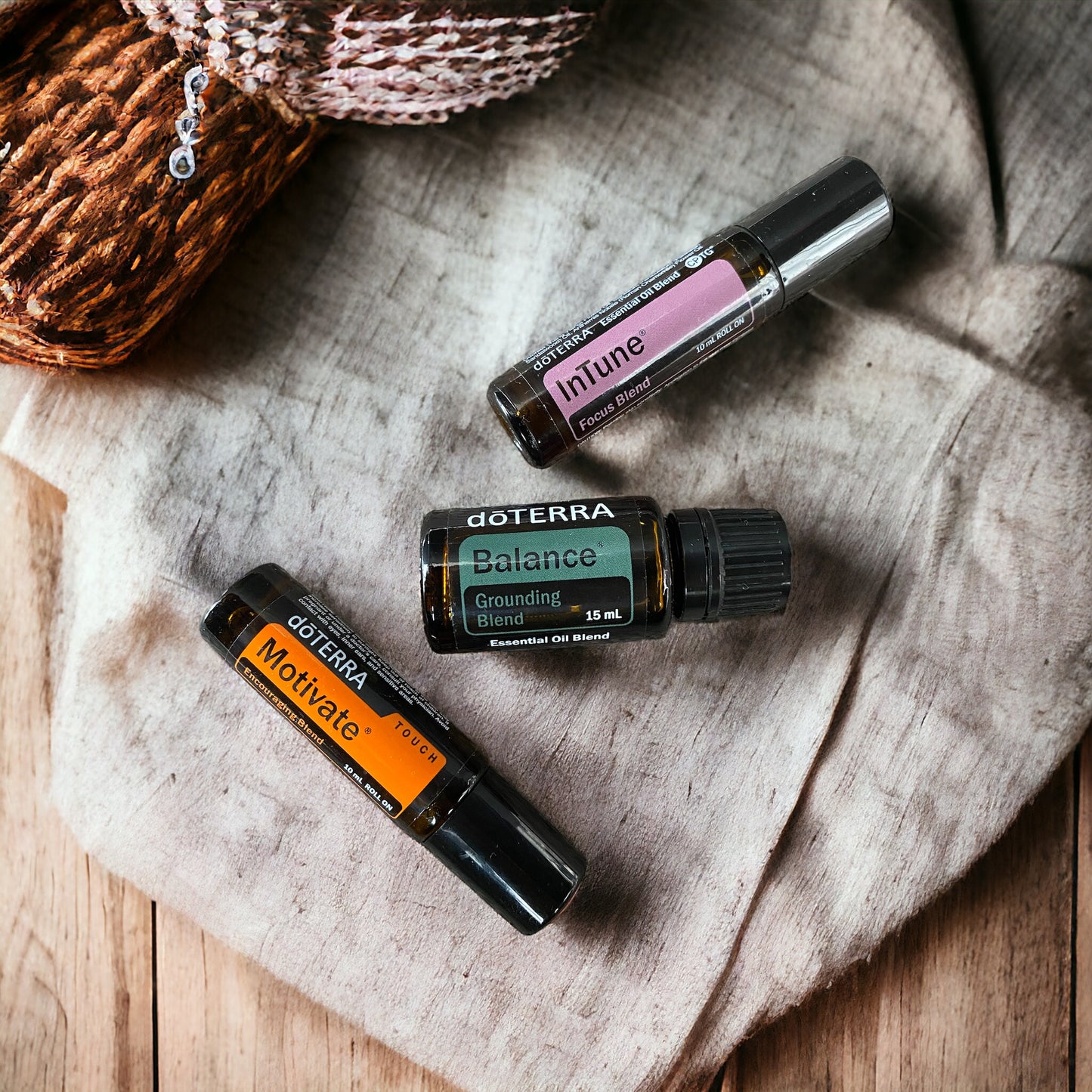 doterra Motivate, doterra Balance and doterra Intune Roll On scattered across a wooden bench.