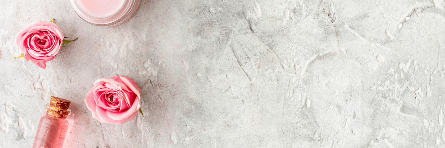 Pink roses and a pink bottle on a light gray textured surface