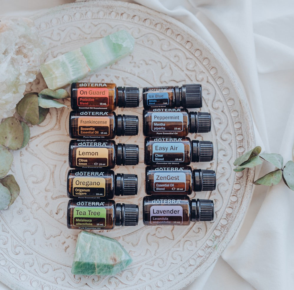 Collection of doTERRA essential oil bottles on a decorative plate with greenery.