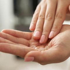 Close-up of two hands with one hand cupping the other against a blurred background