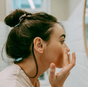 Woman applying skincare product in a bathroom setting