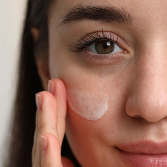 Close-up of a woman applying white cream to her face
