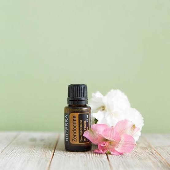 doTERRA Zendocrine essential oil bottle with flowers on a wooden surface and light green background