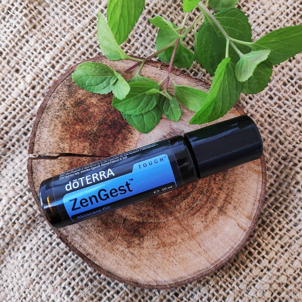 doTERRA ZenGest roller bottle on a wooden surface with green leaves.
