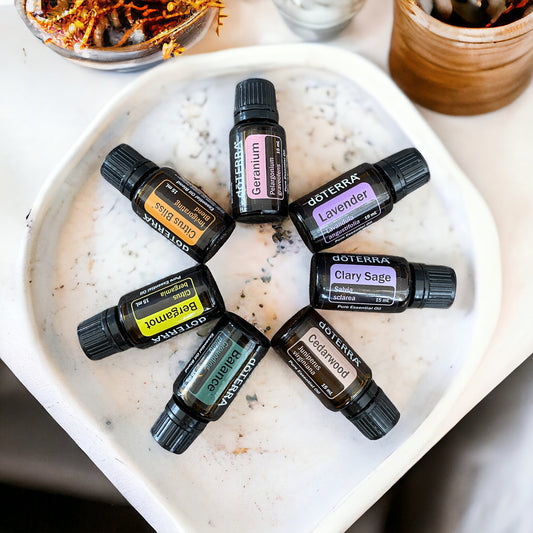 A selection of seven doTerra essential oil bottles, each representing a different color and scent, arranged in a circle in a white dish.