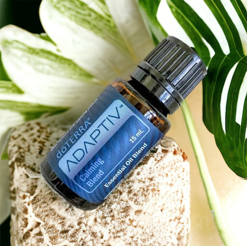 doterra adaptiv calming blend on a rock with white and green flowers behind