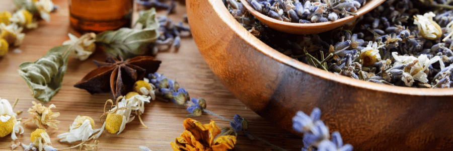 Wooden bowl with dried lavender and other herbs on a wooden surface