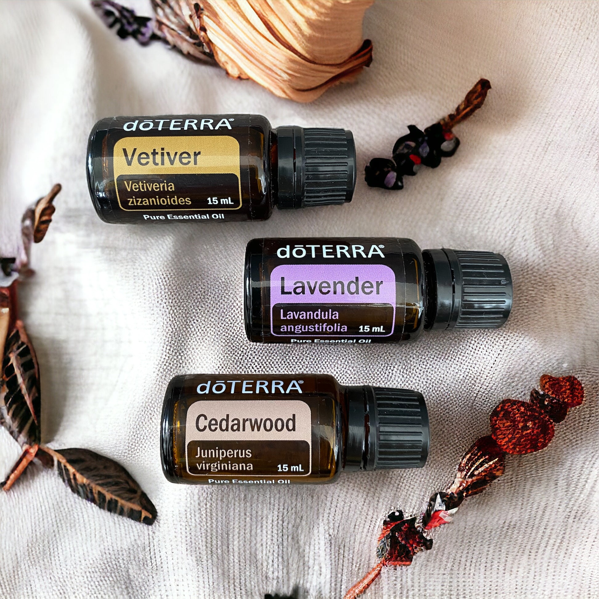 doterra vetiver, doterra lavender and doterra cedarwood essential oils laying on a linen cloth surrounded by natural elements.