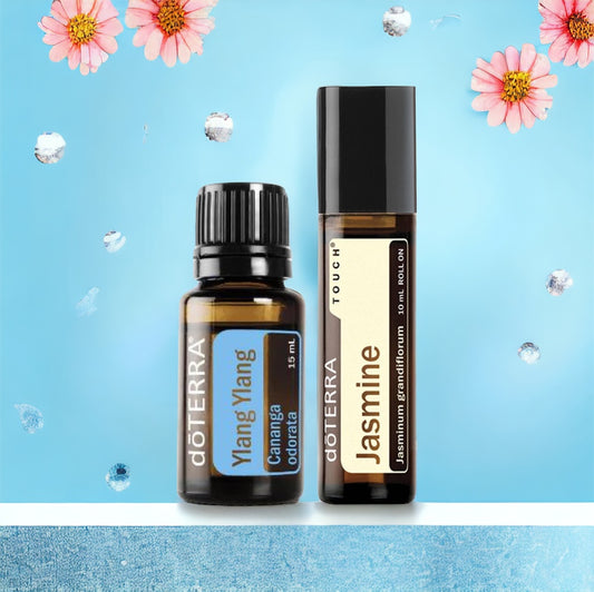 Two bottles of doTerra essential oils, one labeled Jasmine Touch and the other Ylang Ylang, set against a blue backdrop with flowers.